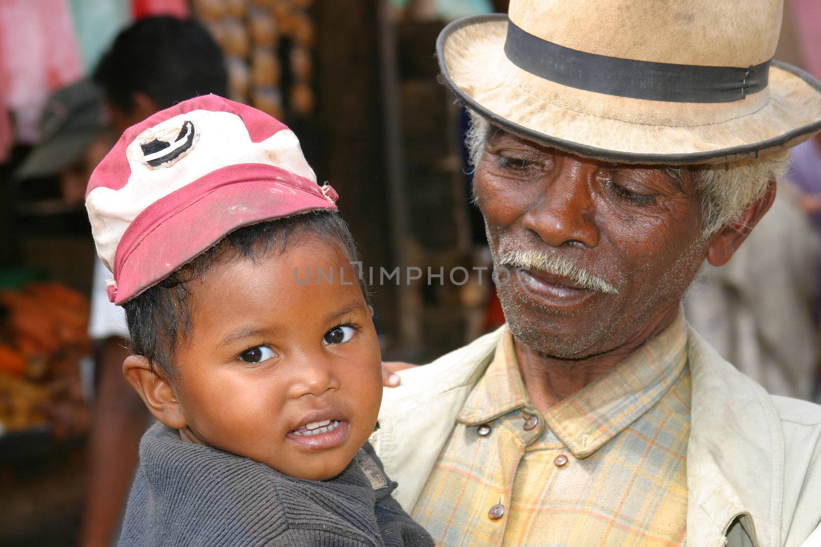 Elderly gentleman at a market in Madagascar showing off his grandchild