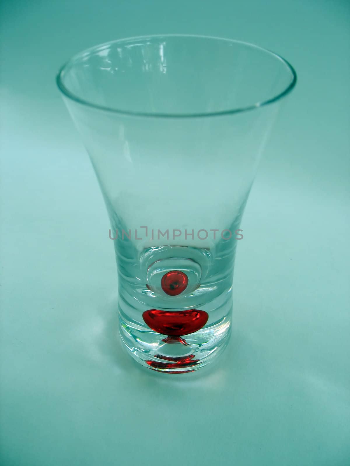 a unique isolated shot glass.  red glass bubble in the base.