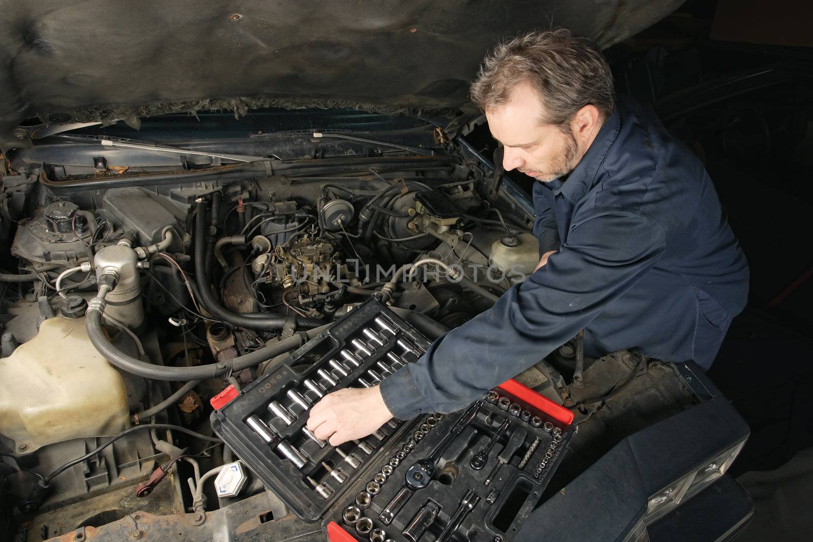A mechanic repairing an engine of an old car.