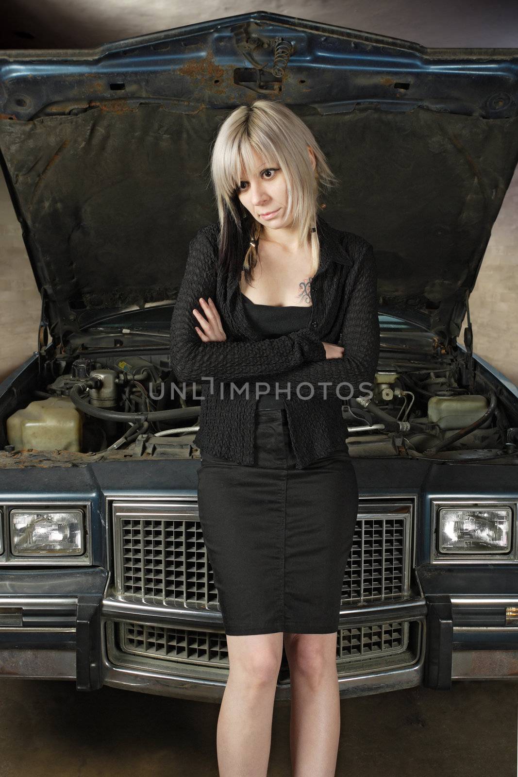 A frustrated blond female in her 30's waiting for a mechanic to fix her car.
