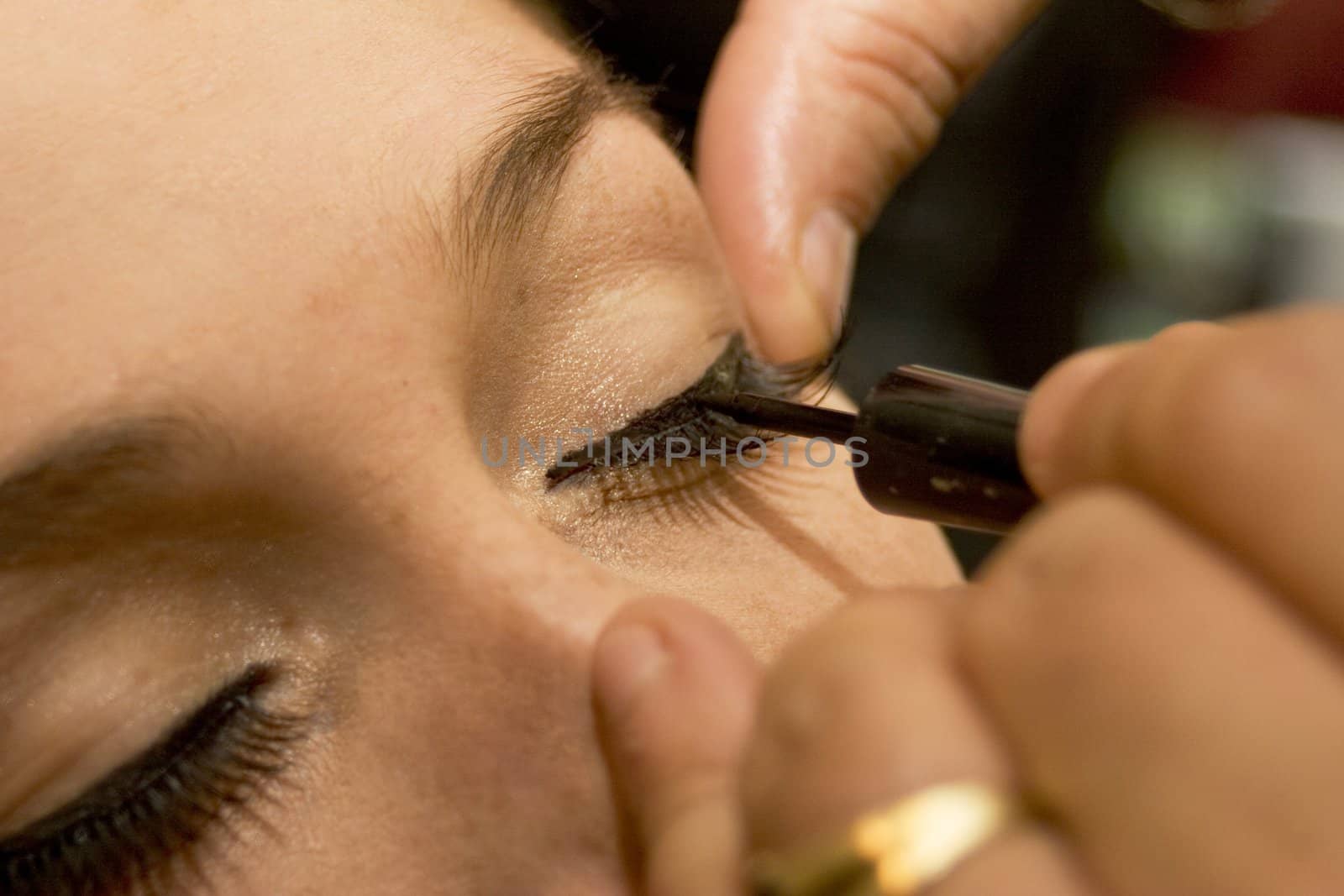 Professional make-up artist applying liner to eyes 