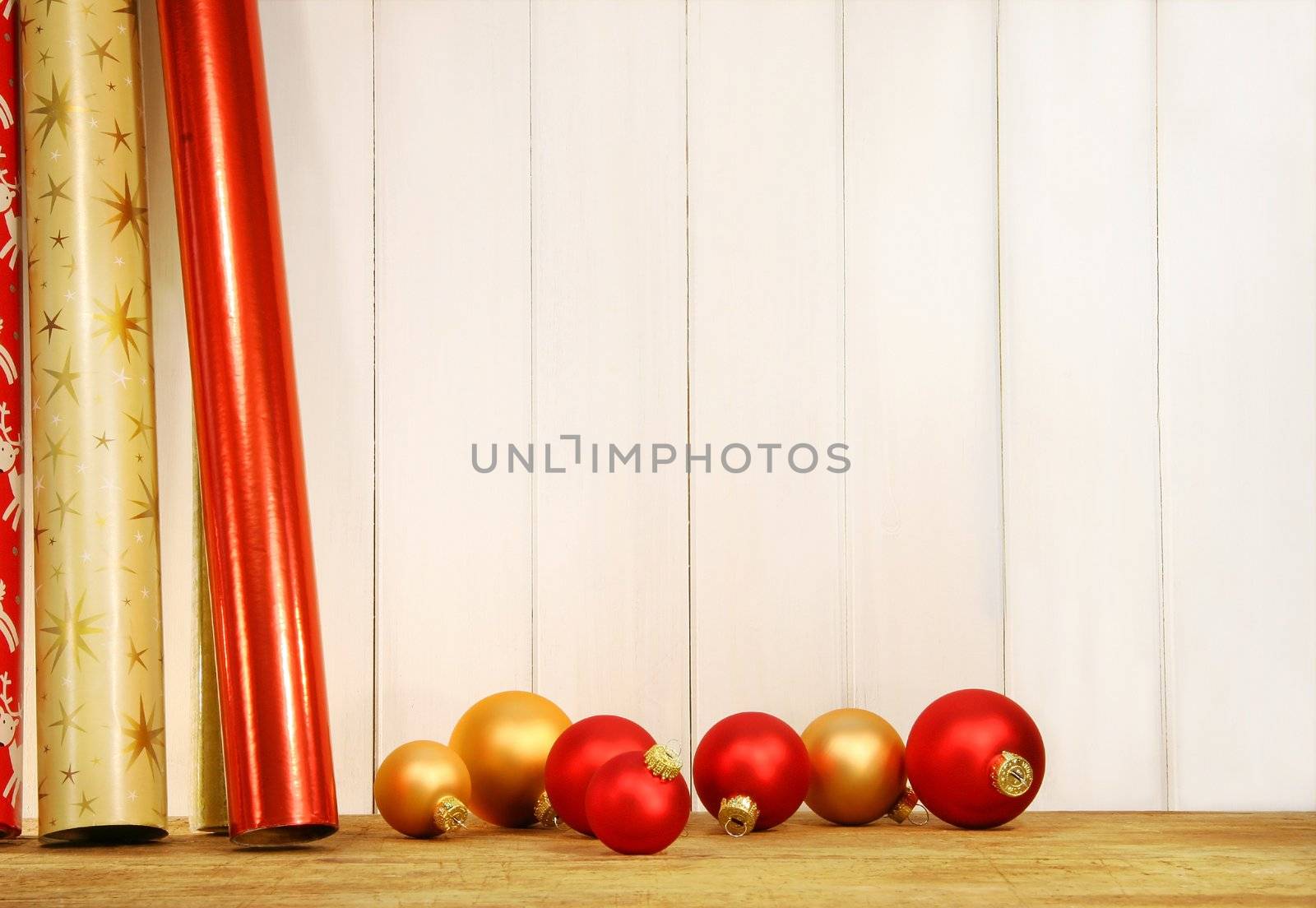 Rolls of holiday wrapping paper against wall with glass balls