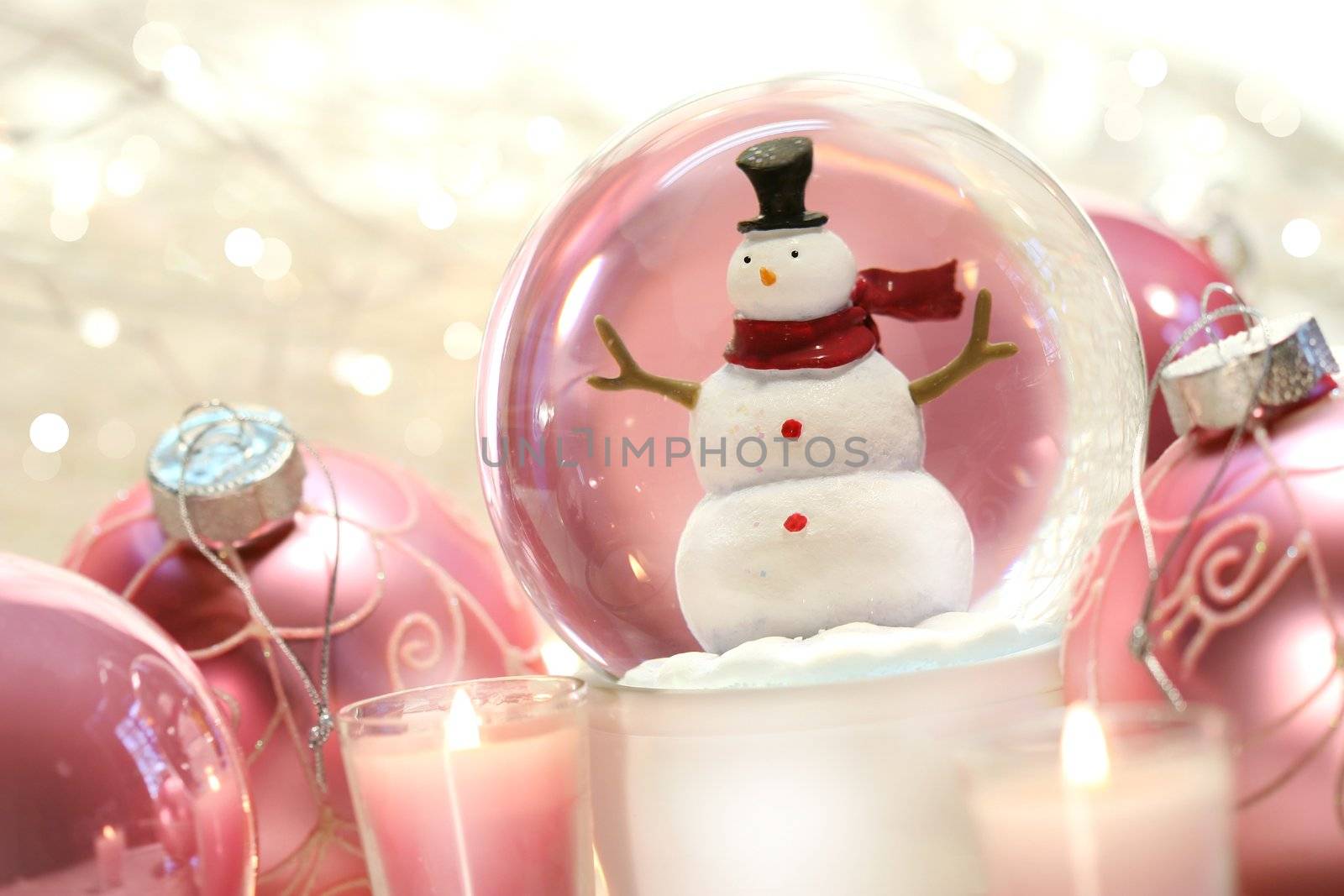 Snow globe with pink christmas balls and white lights in background