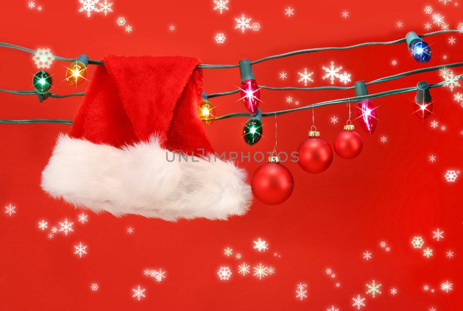 Hanging lights with santa hat and christmas balls against a red background