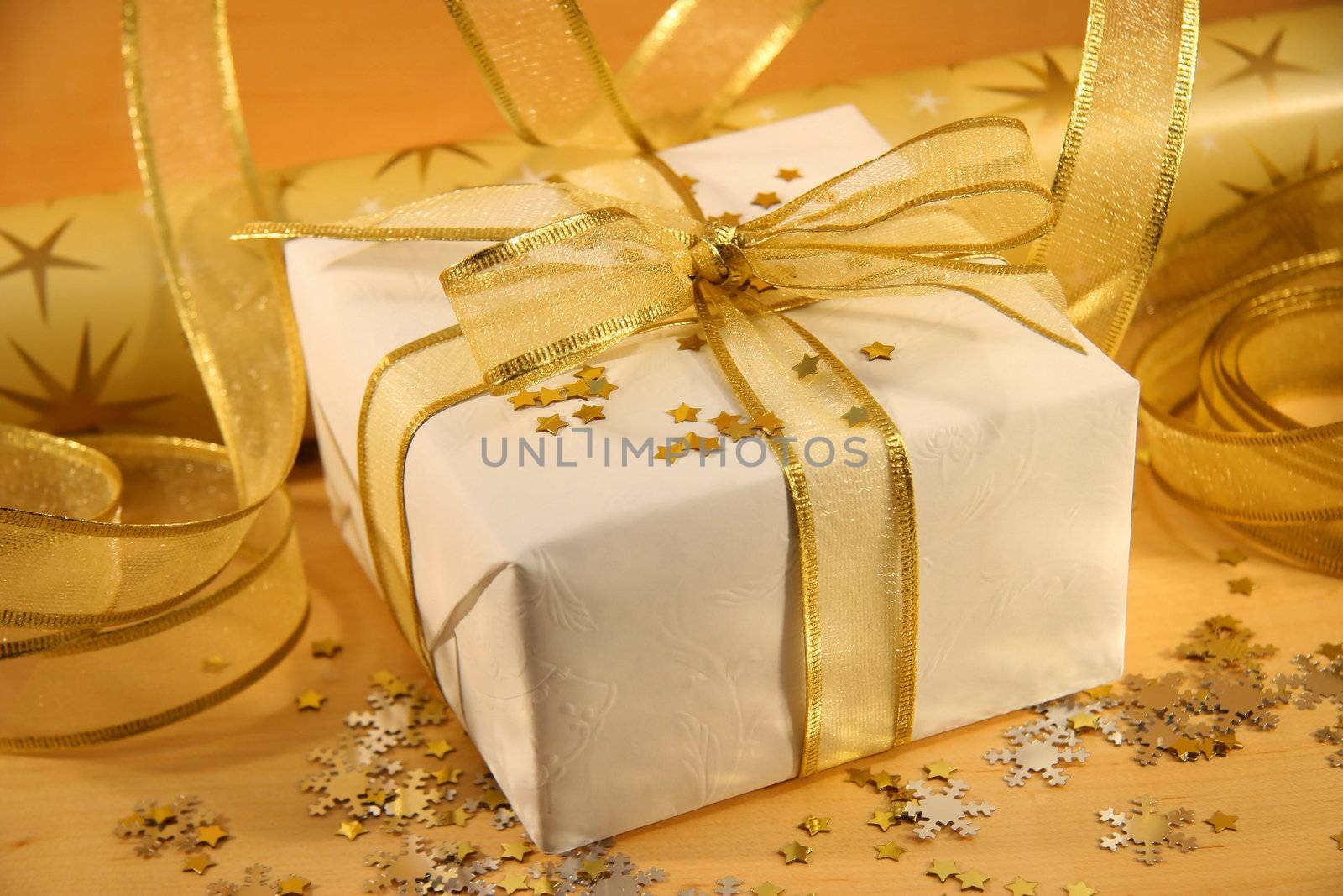 Christmas gift wrapped with white and gold paper and bow