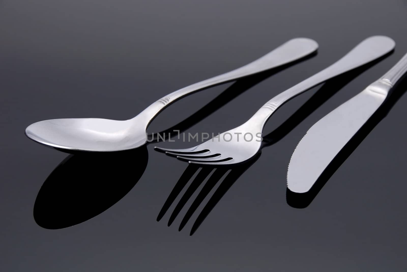modern silver spoon, knife, fork on the mirror background