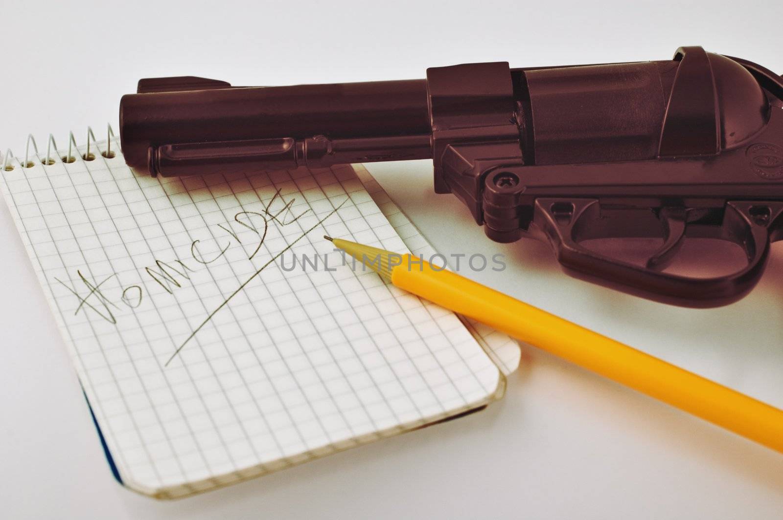 Close-up of a notepad with word 'homicide' written with pencil and gun with selective focus
