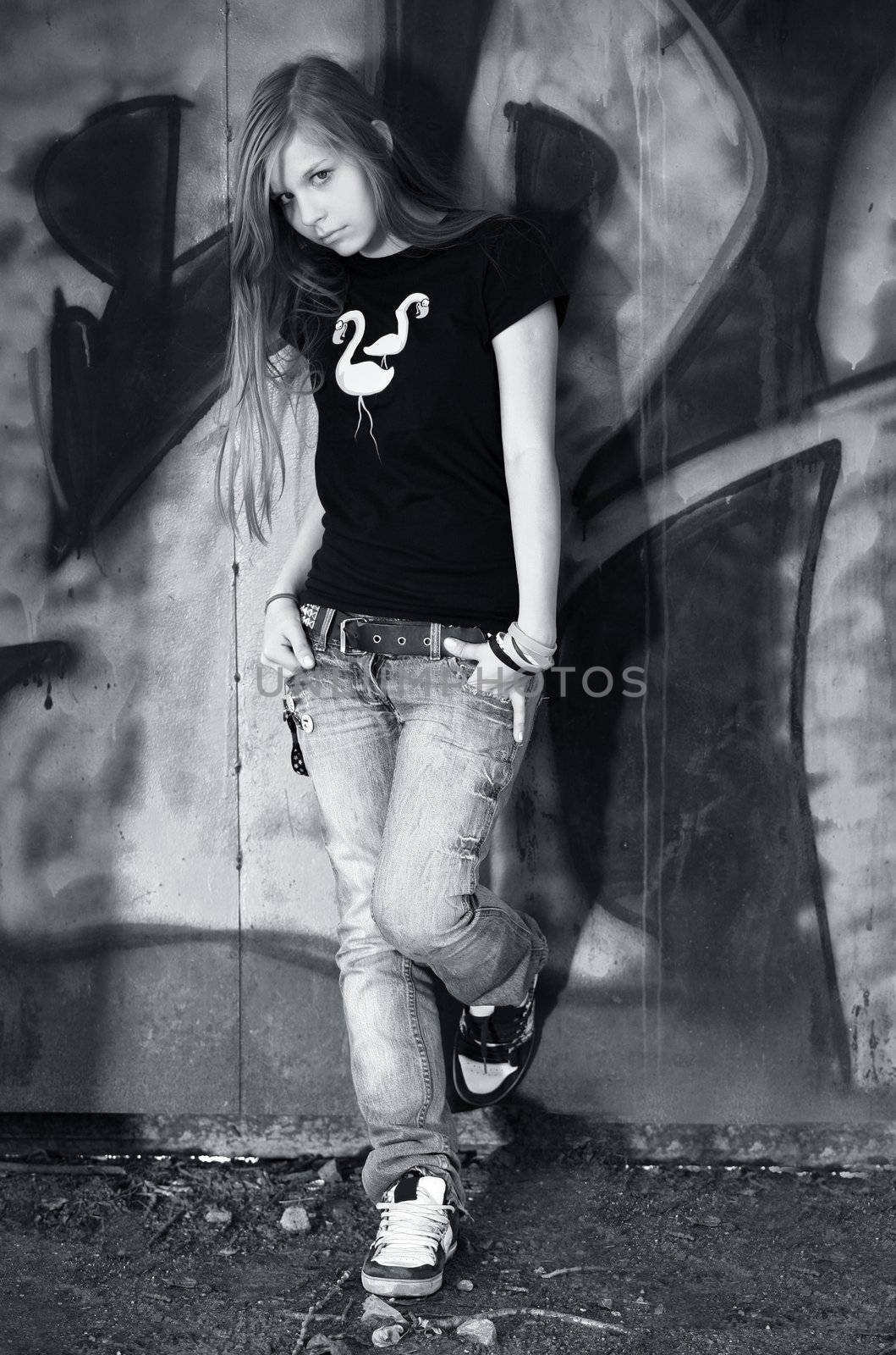 The young girl on a background of a wall with graffiti
