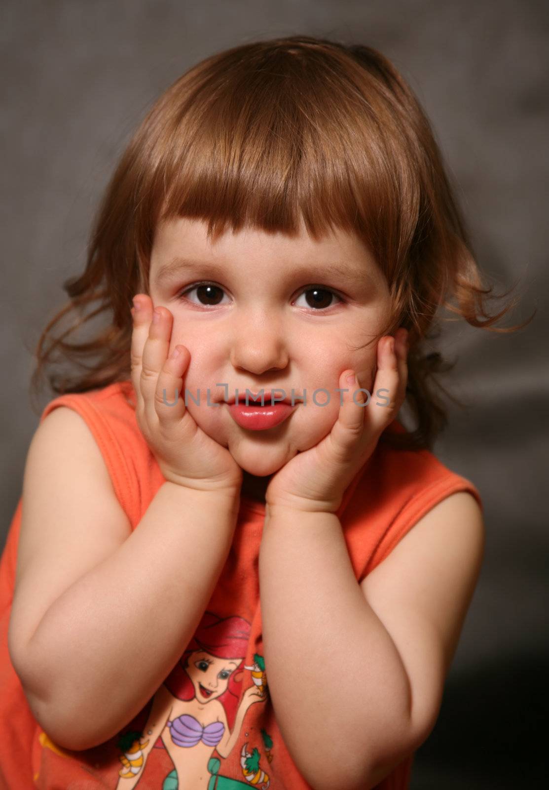 Portrait of the two-year-old girl which behaves hands for the face