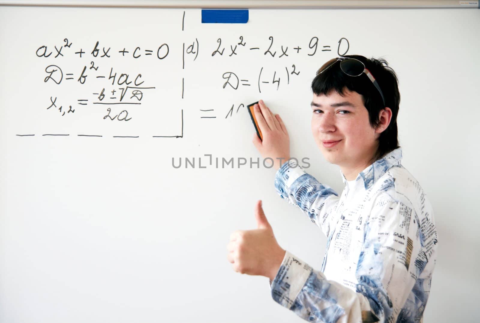 Young teacher teaching algerbra  and writes quadratic equation on a whiteboard