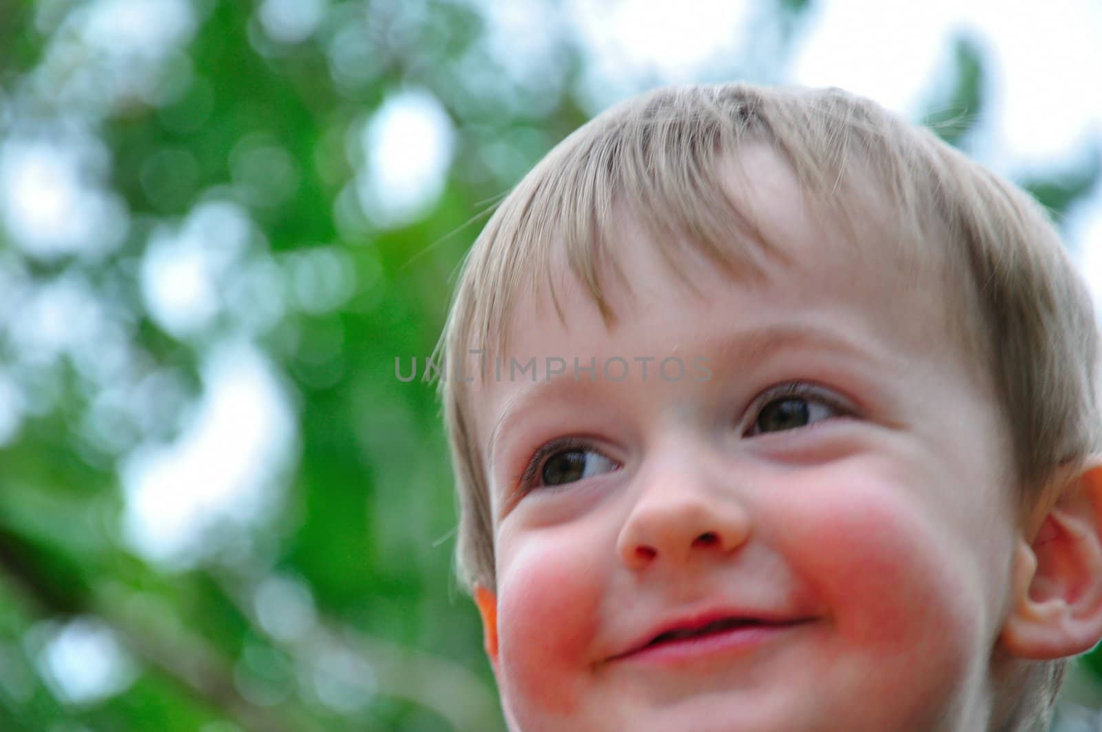 A toddler boy smiles and plays outside in Spring.