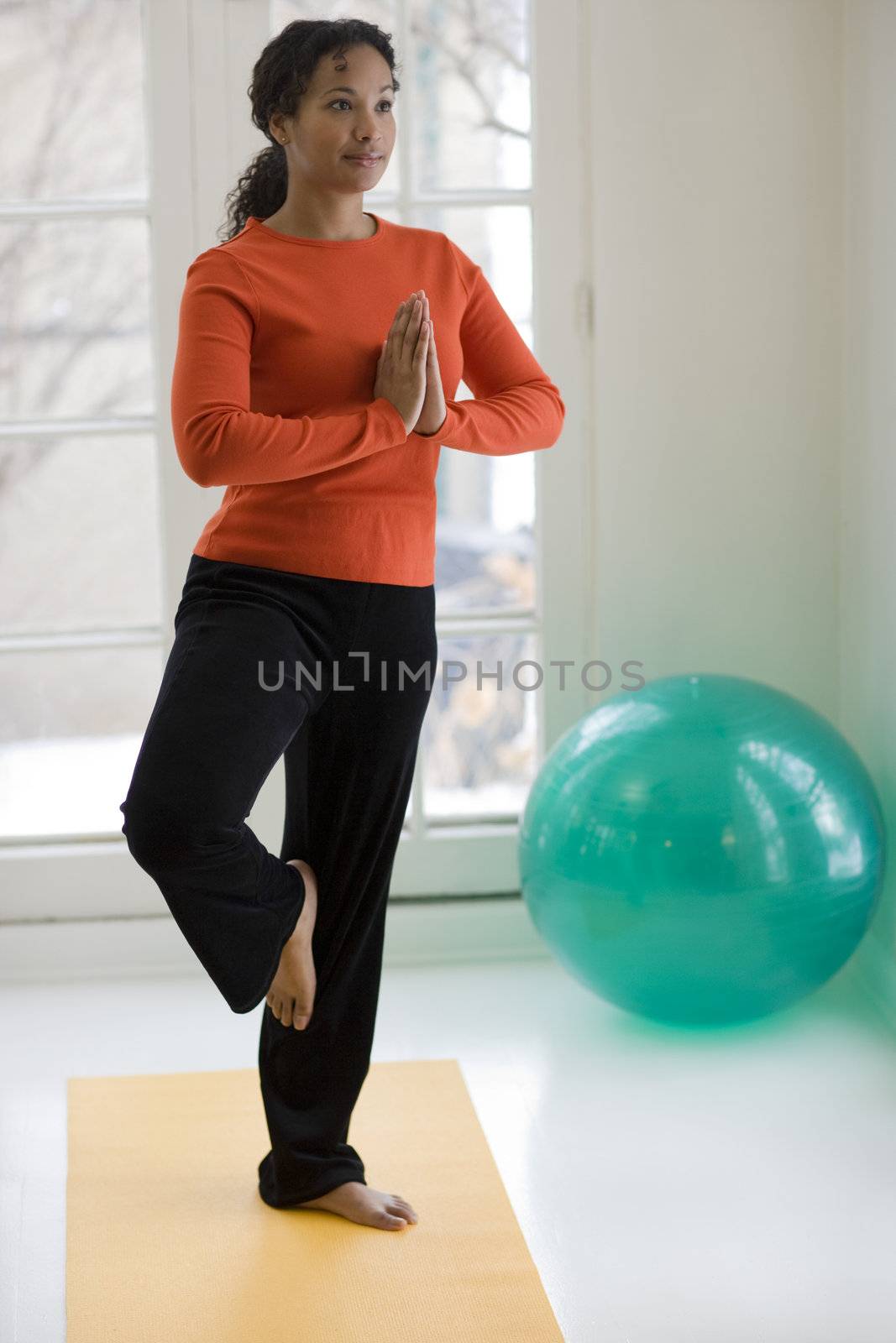 Young African American woman in yoga Tree pose at home