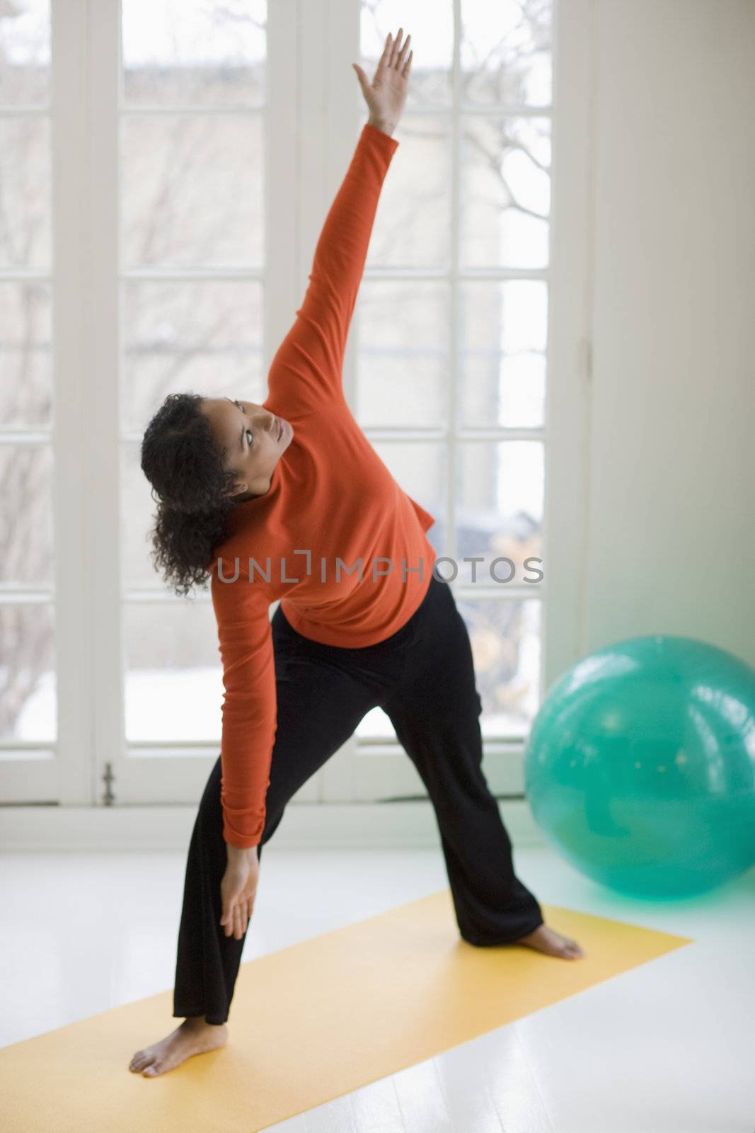 Attractive young African American woman in yoga Warrior pose at home