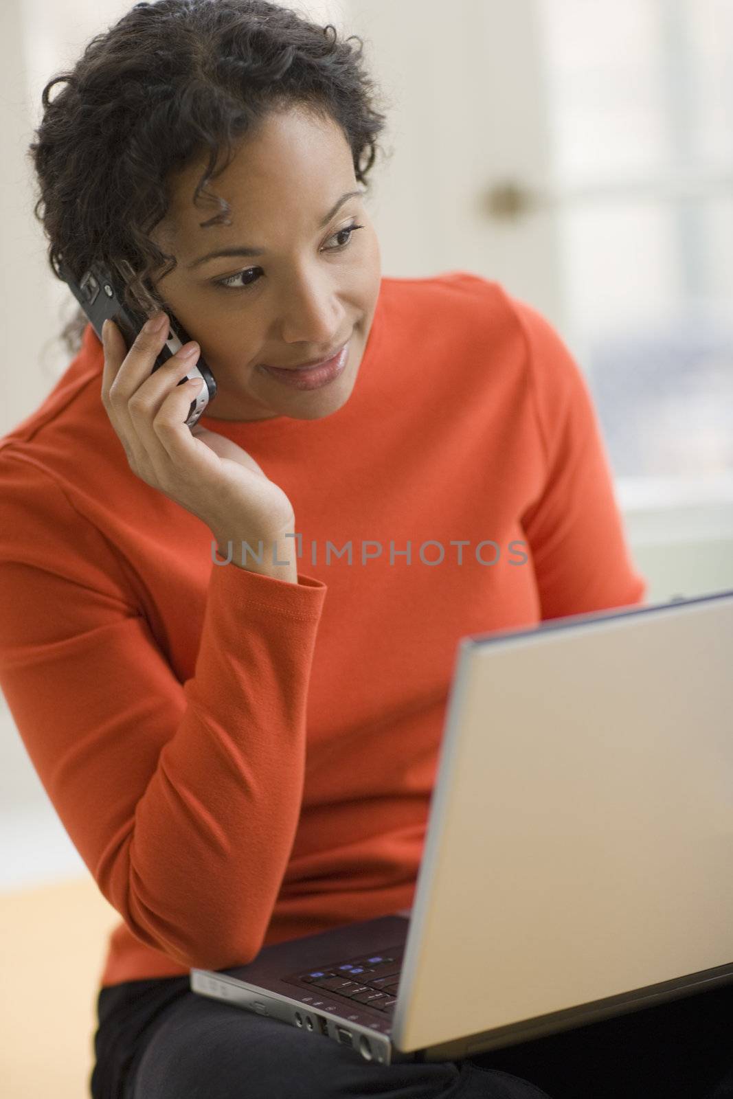 Black woman on cell phone and laptop by edbockstock