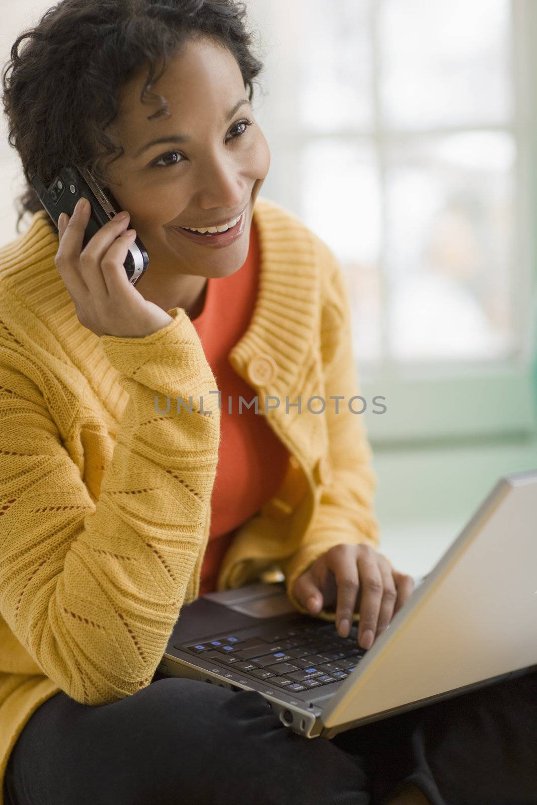 Pretty black woman on cell phone and laptop by edbockstock