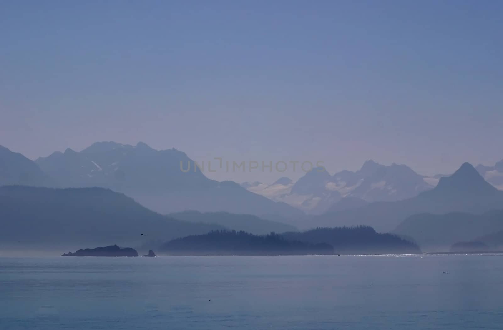 Mountains and glaciers seem shrouded in mystery as day breaks over the misty, chilly waters of Katchemak Bay off the Kenai Penninsula in Alaska