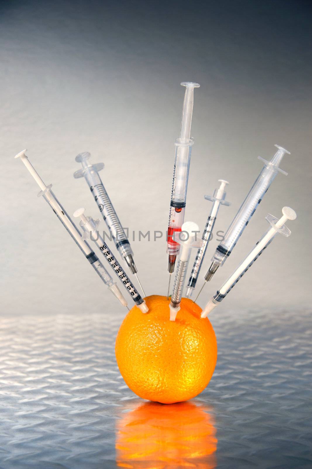 Syringes inserted into an orange by Sandralise