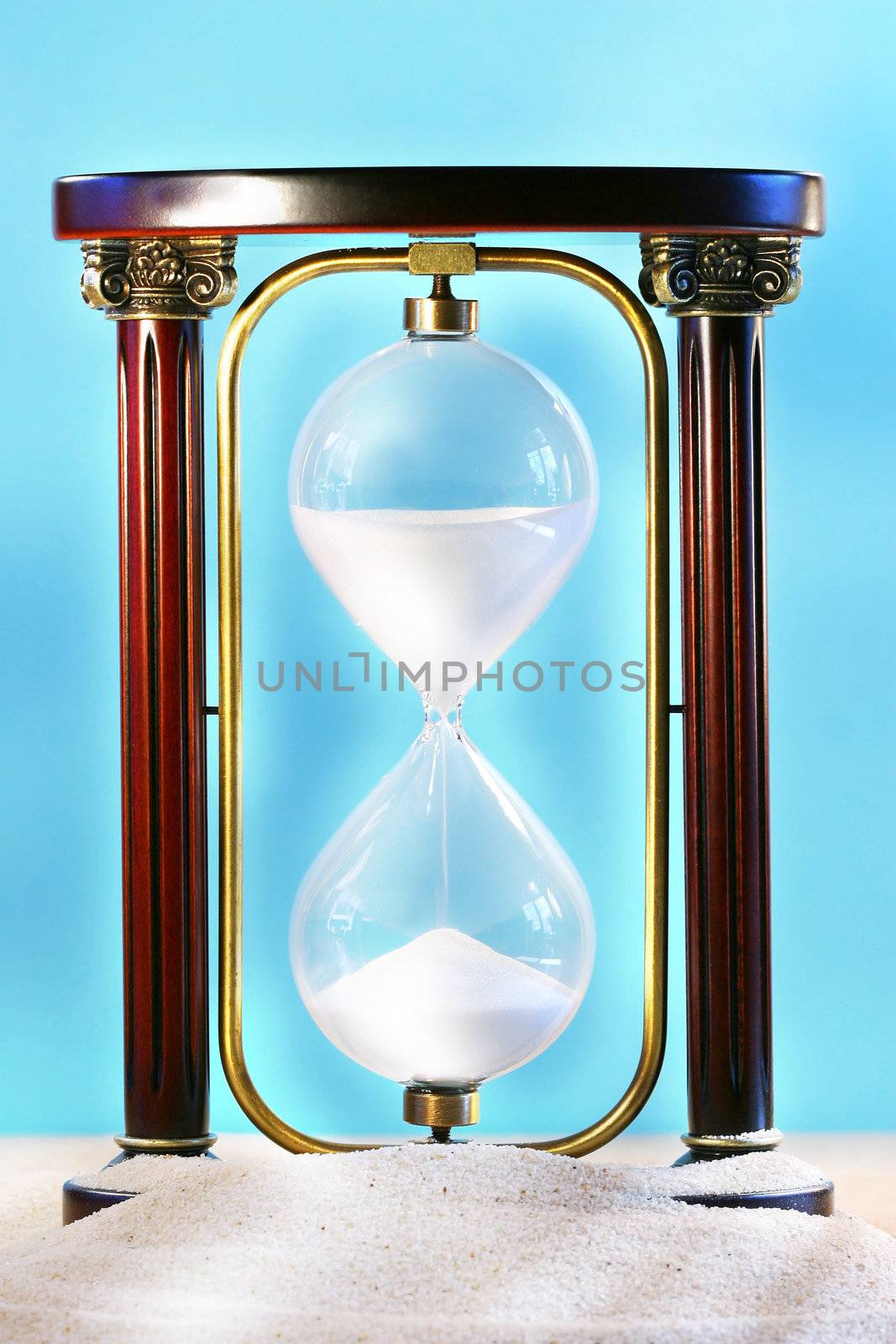 Hourglass resting on beach sand showing sand falling through glass