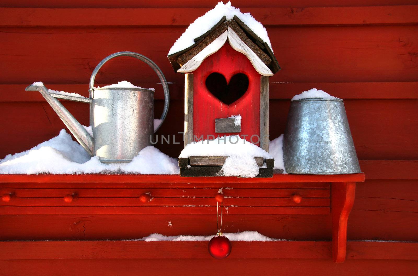 Old red birdhouse on shelf in the snow