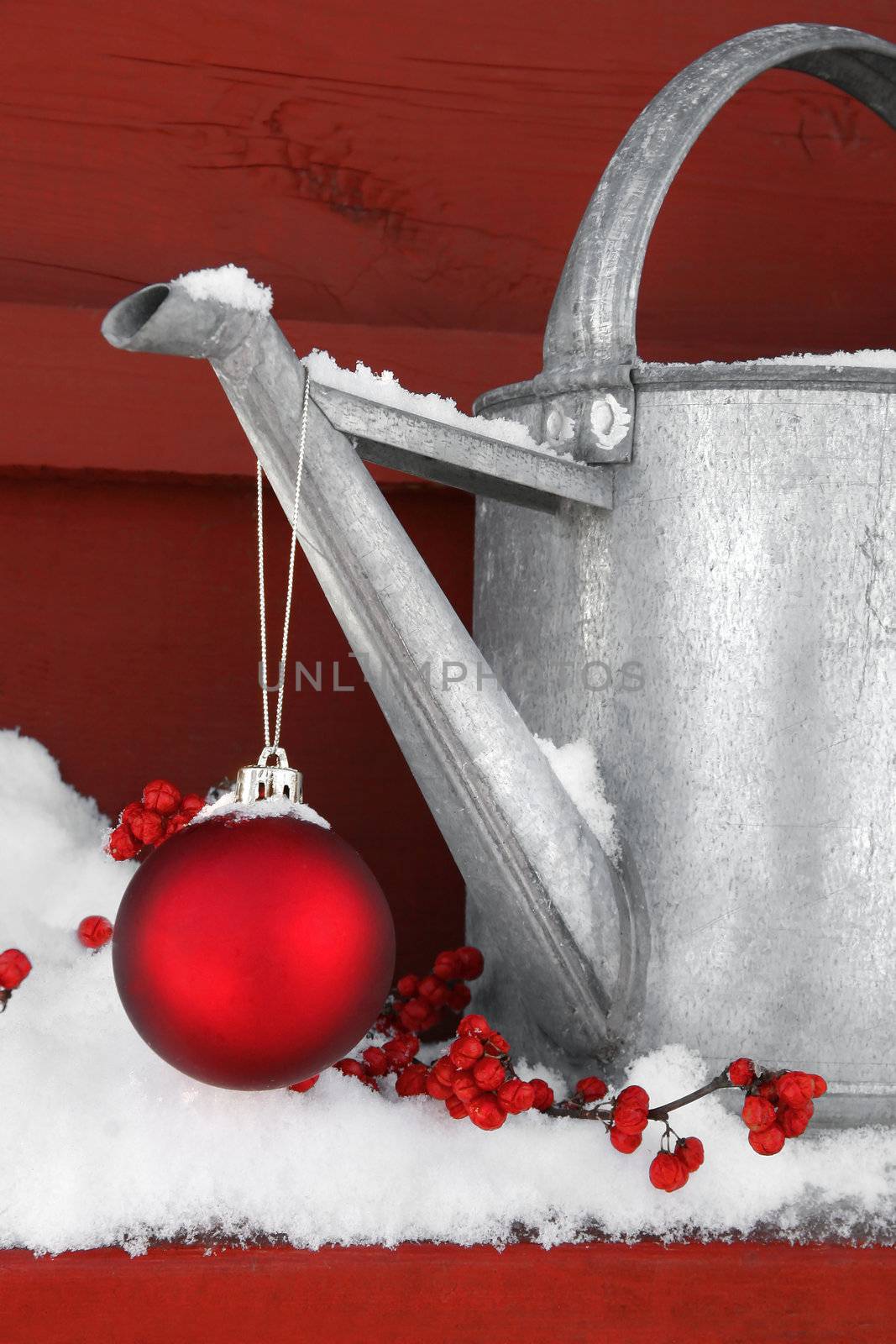 Red Christmas ball hanging on watering can in the snow