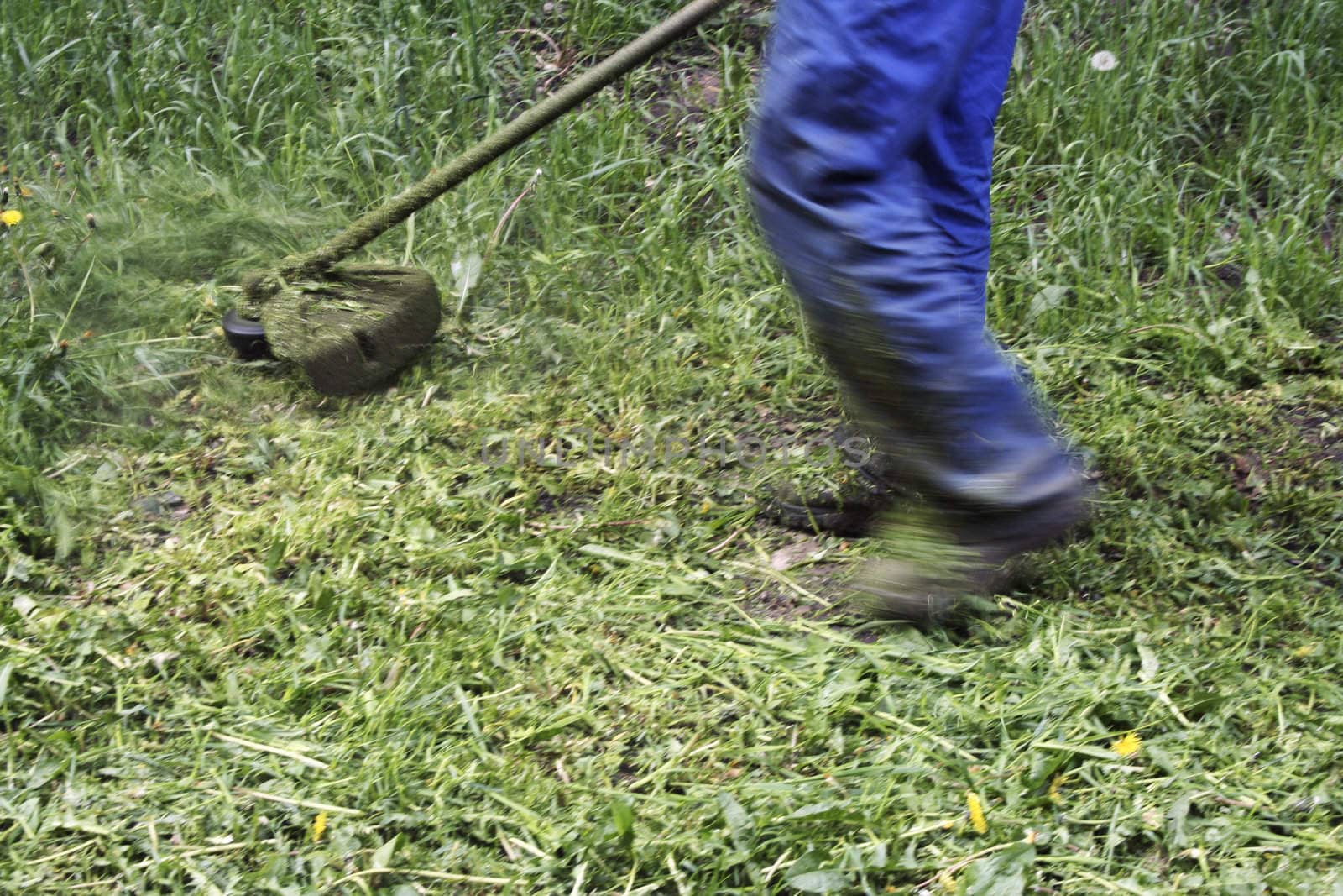 motor scythe by close up and feet of haymaker