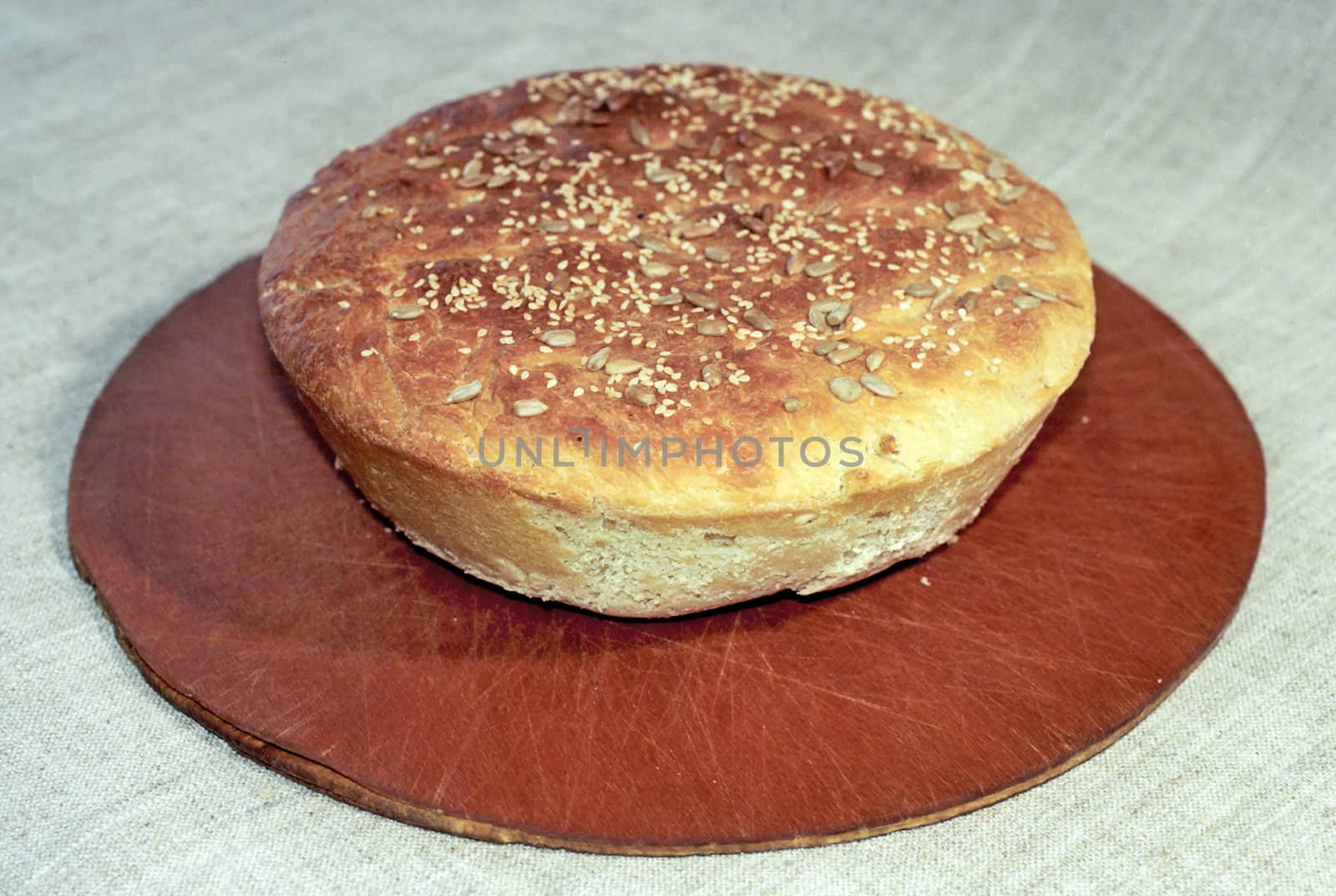 Round loaf of bread on wooden breadboard