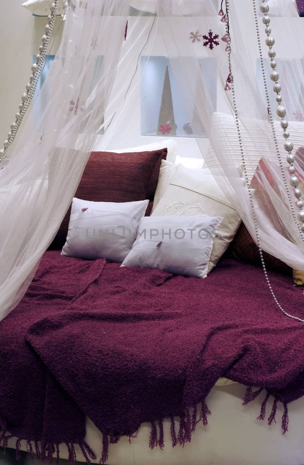 Round bed with pillow by coverlet, transparent blind and decorations