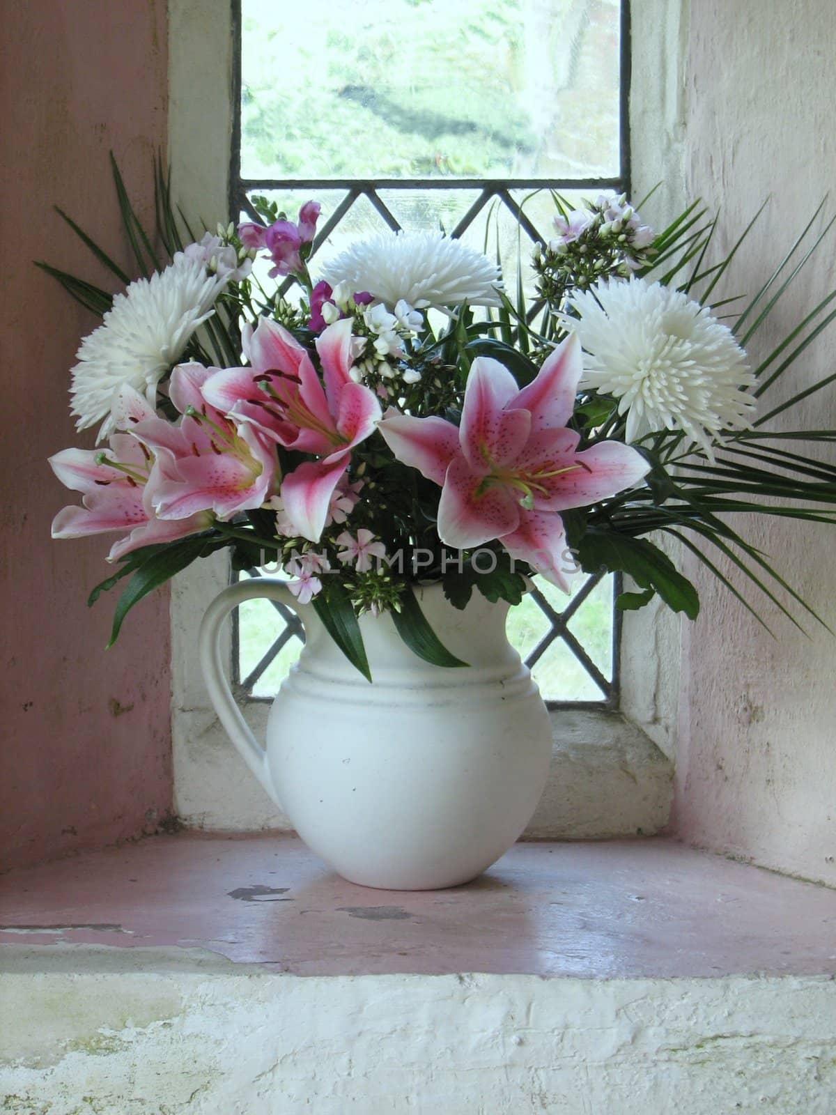 bunch of pink and white flowers standing in a window