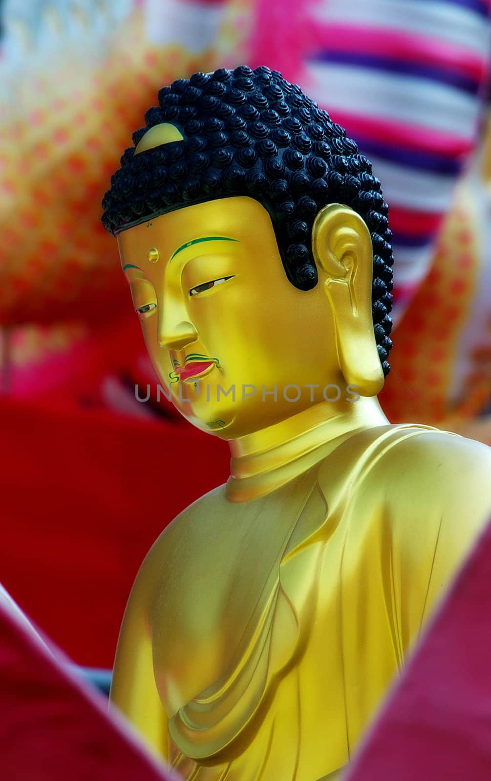 A golden buddha sitting against a colorful background. Busan, South Korea.