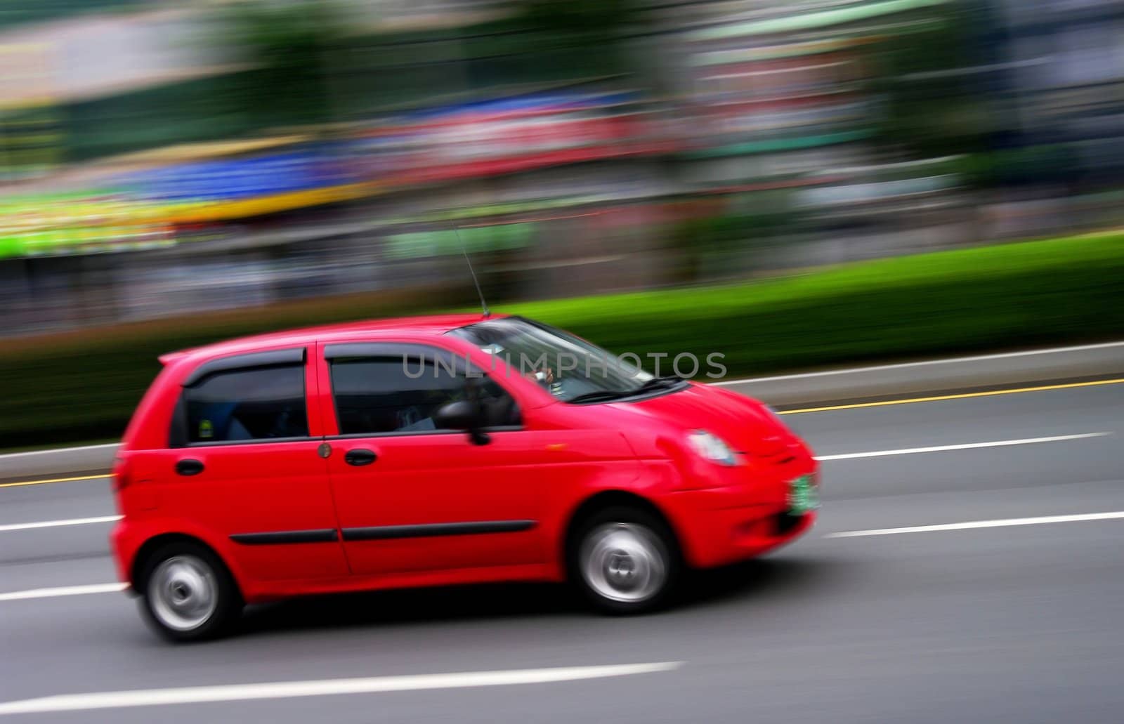 A red car speeding through a city centre. Motion blur was used for effect.