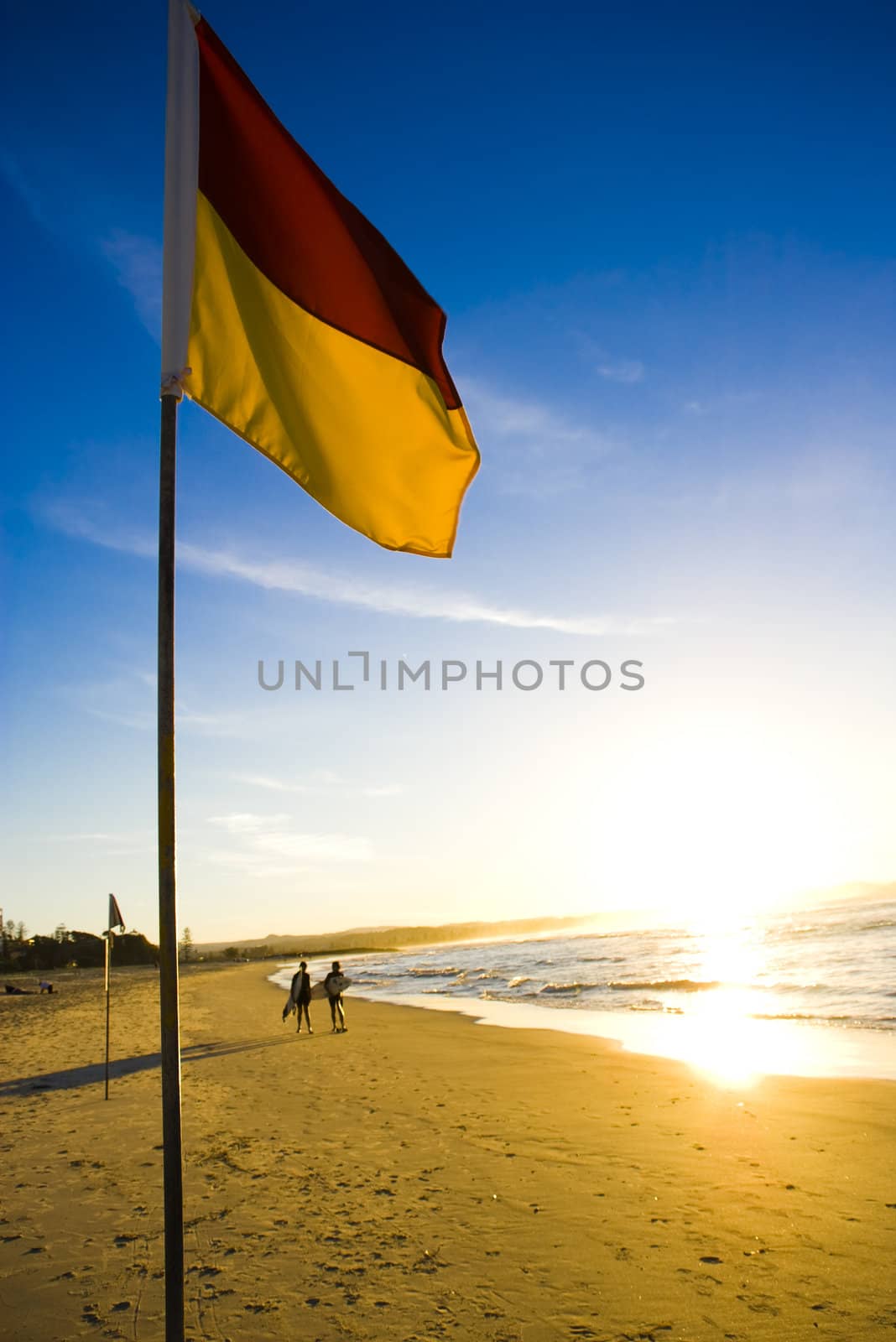 A surf life saving flag in Australia to mark the safe place to swim at the beach just before sunset