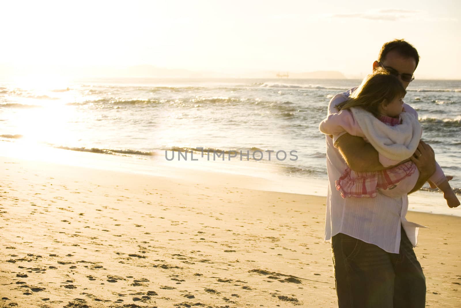 Sunset at the beach with a young father and his little girl