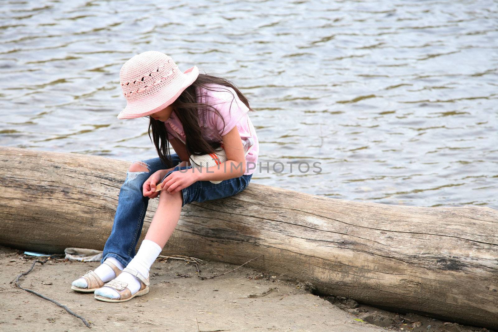 Girl with wound sitting on log by river