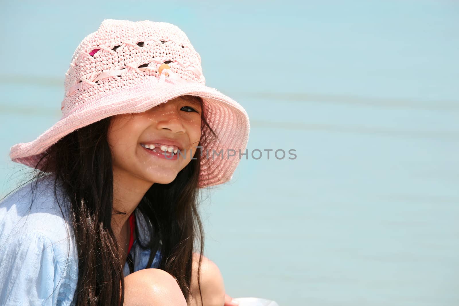 Cute little girl in pink hat at beach