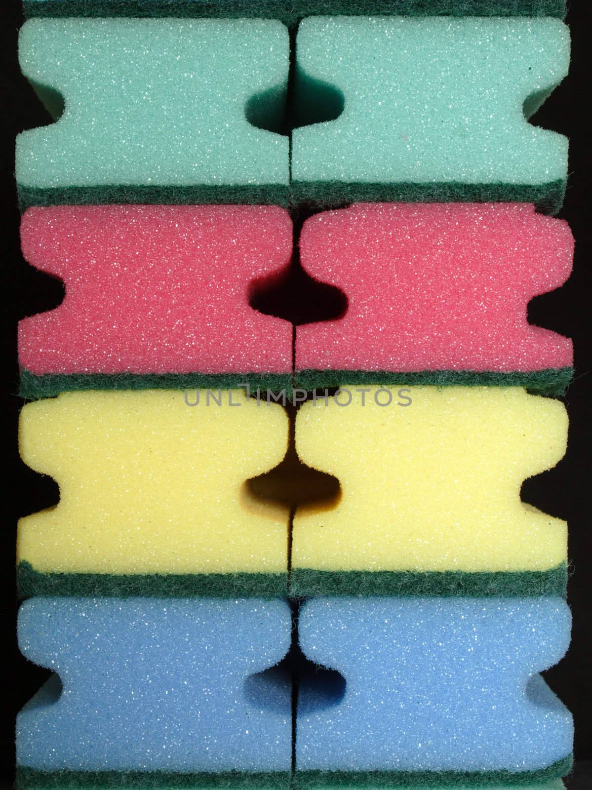 Colourful cleaning sponges against a black background.