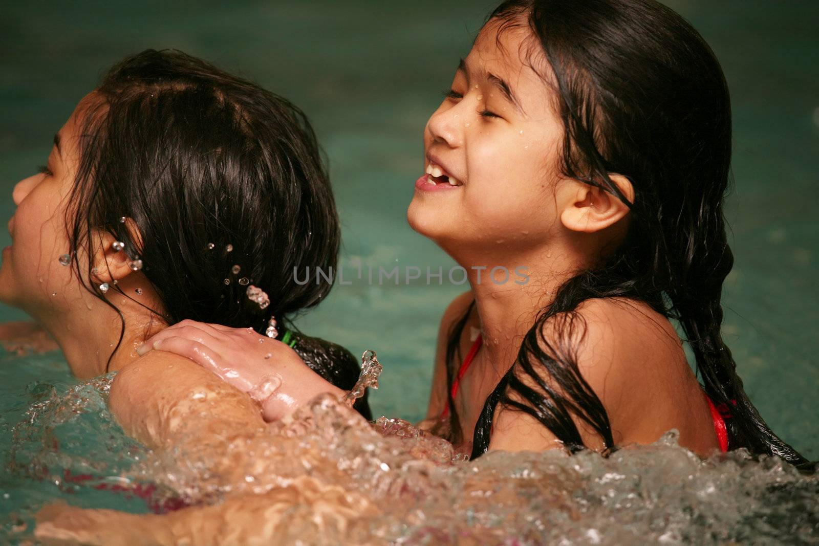 Two girls in swimming pool playing together