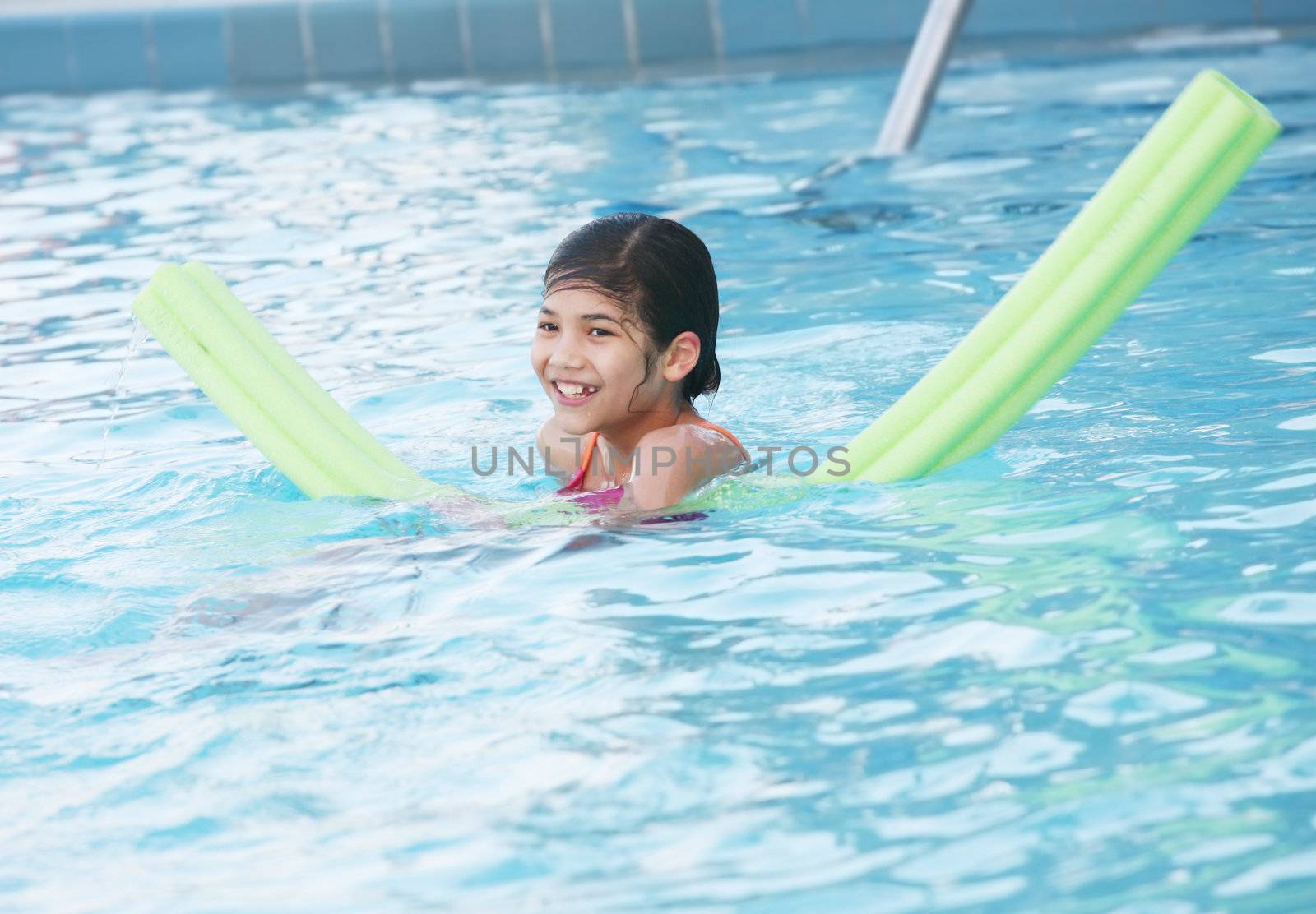 Little girl swimmnig in pool with floatation toy