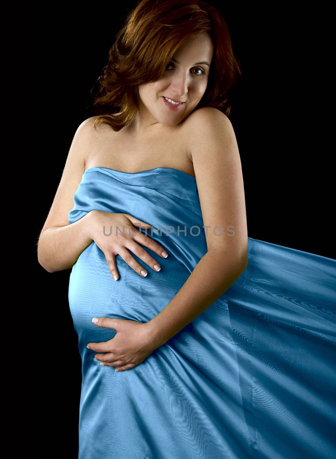 Pregnant woman posing on a black background with beautiful dress