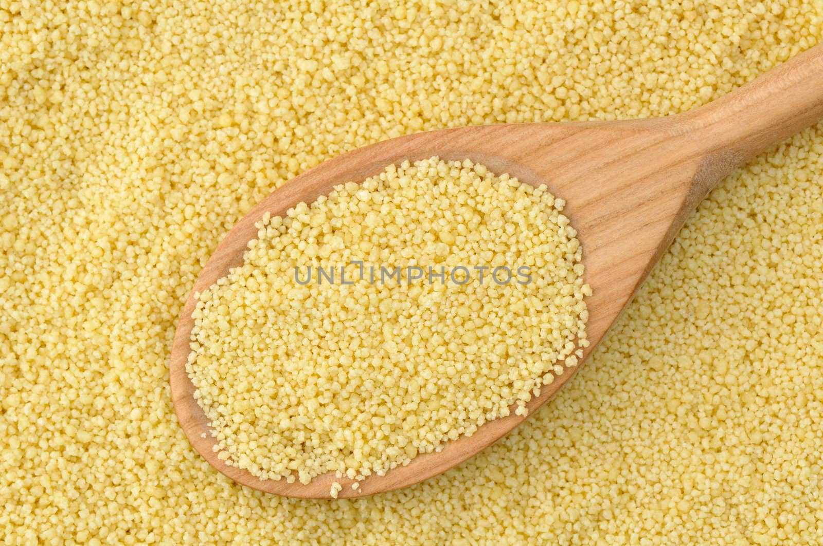 Wheat semolina couscous background with wooden spoon
