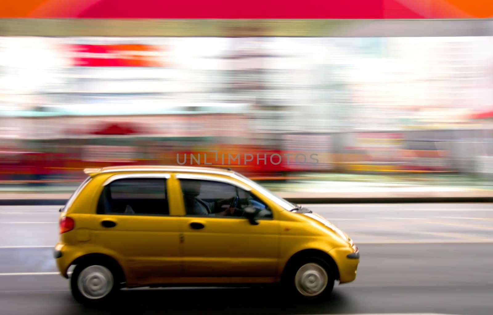 A yellow car speeding through a city center. Motion blur was used for effect.