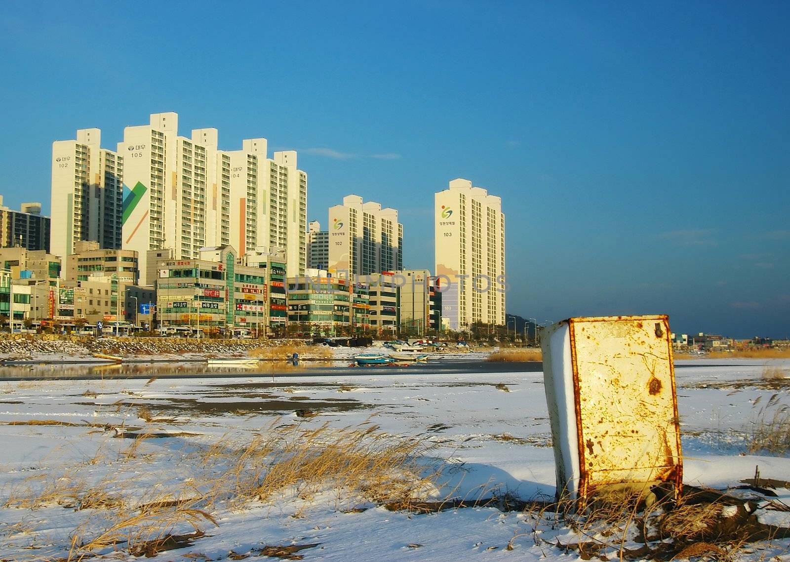 An abandoned fridge sits in the snow on Dadaepo Beach, Busan, South Korea. A visual metaphor for resource waste.