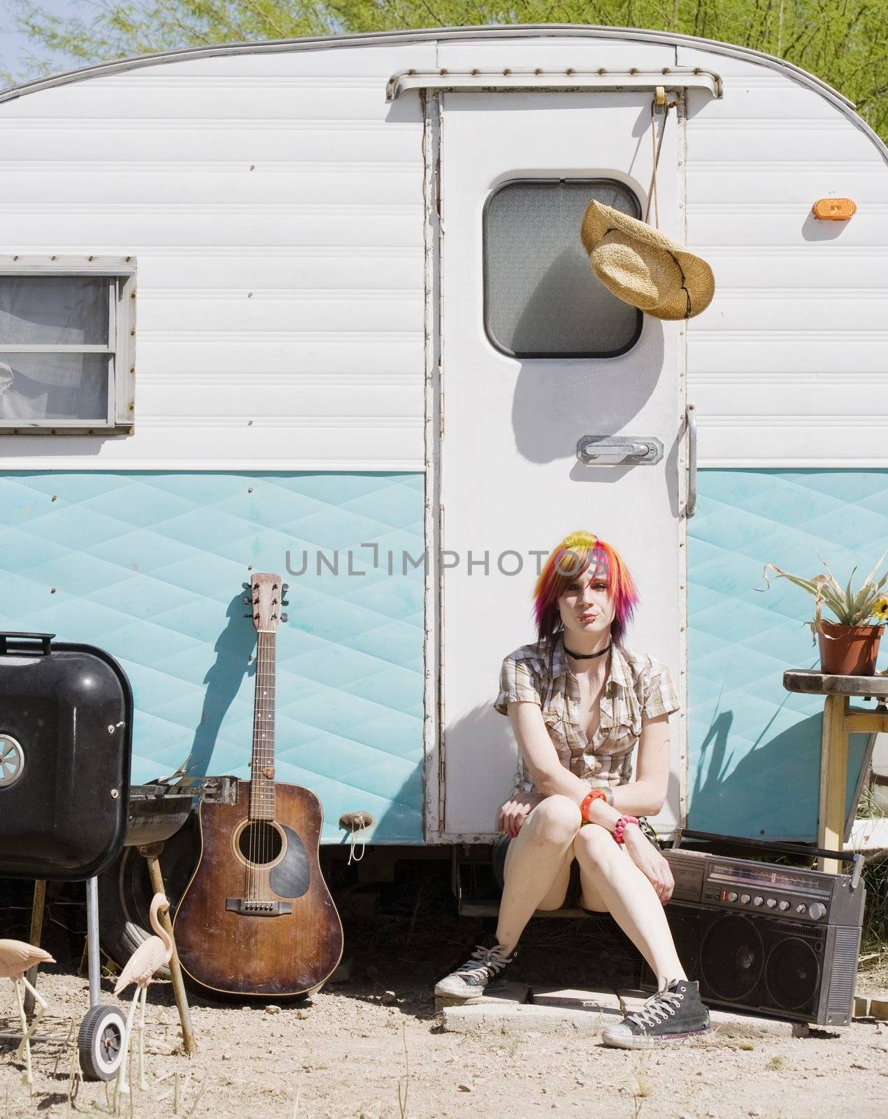 Punk girl with brightly colored hair sitting on a trailer step