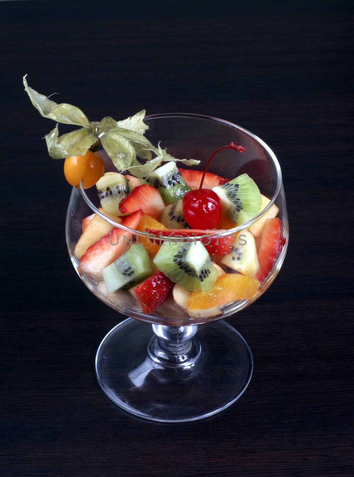 fruit salad in tall wine glass on dark background