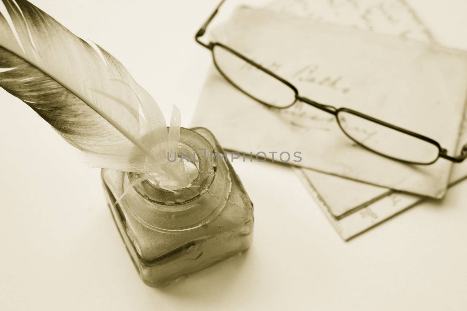 Sepia toned image of an ink pot with feathered quill and hand written letters (recreated by self) and a pair of reading glasses.