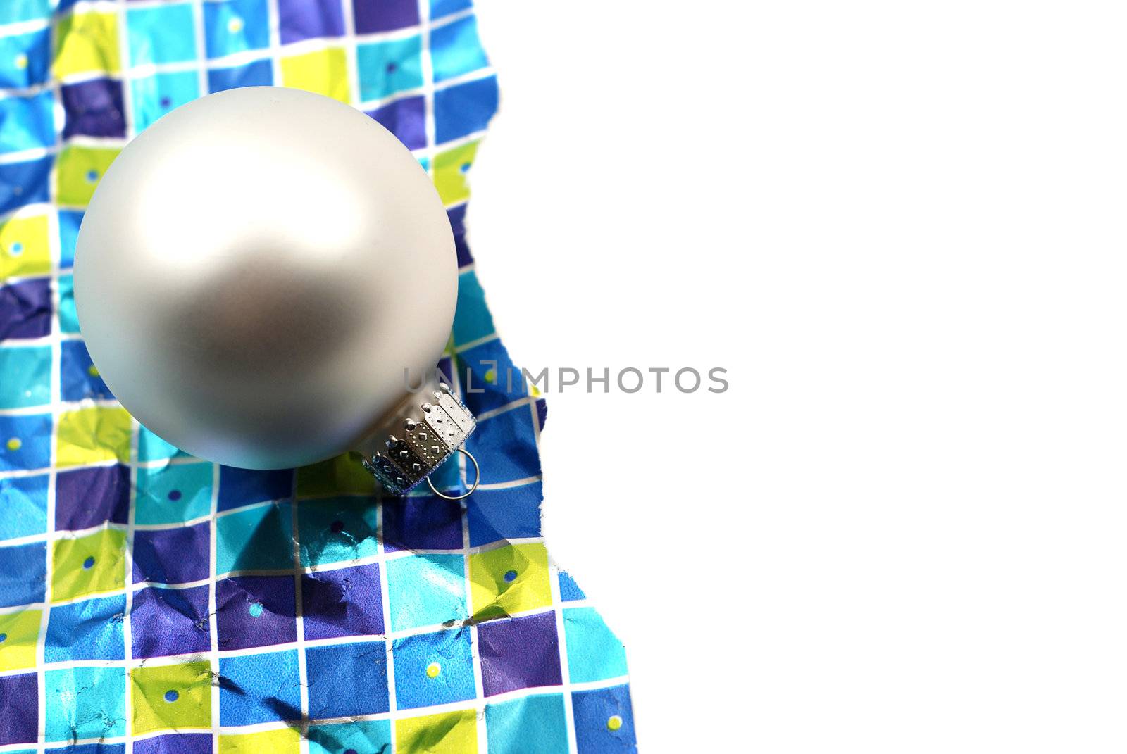 Holiday decoration ornaments resting over wrinkled used torn wrapping paper on white background