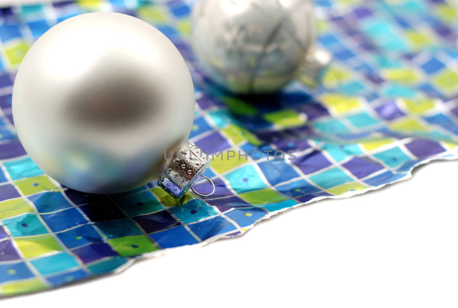 Holiday decoration ornaments resting over wrinkled used torn wrapping paper on white background