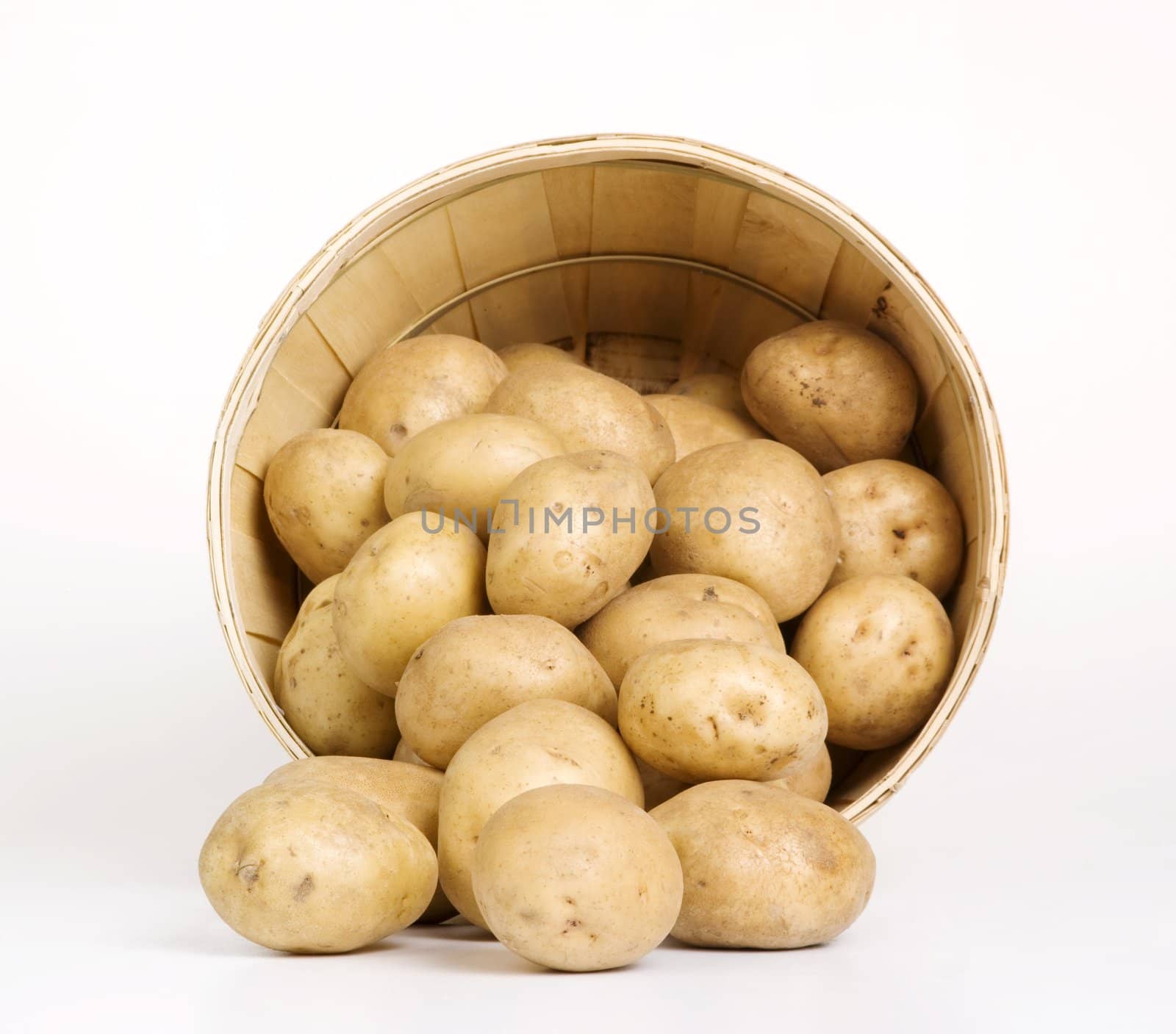Patatoes in a woven basket on a white backround