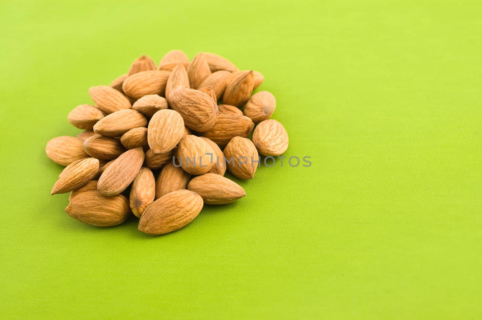 Group of almnonds on green background, close up.