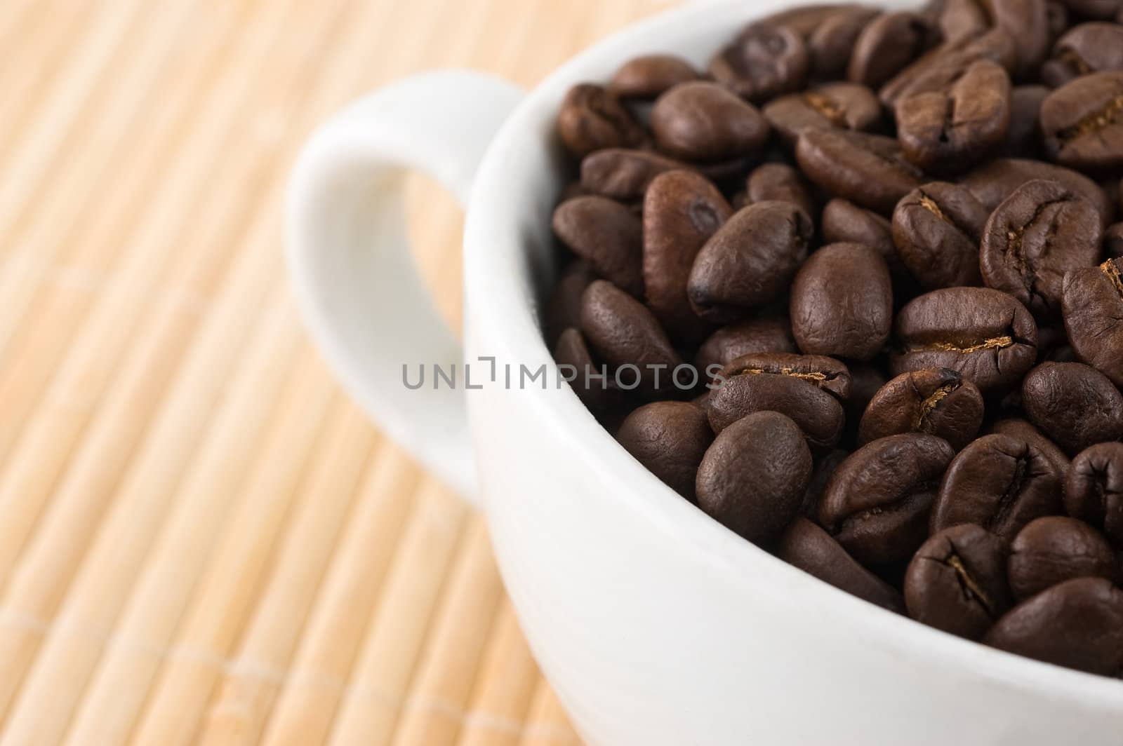 coffe grains and cup on bamboo mat, close up-