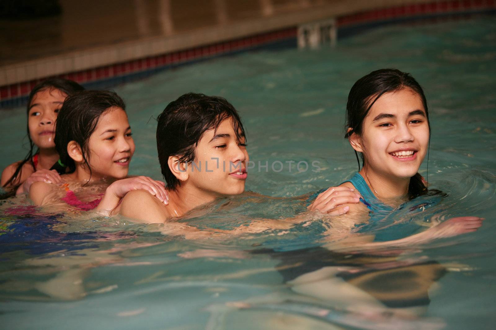 Four children swimming together, having fun in pool